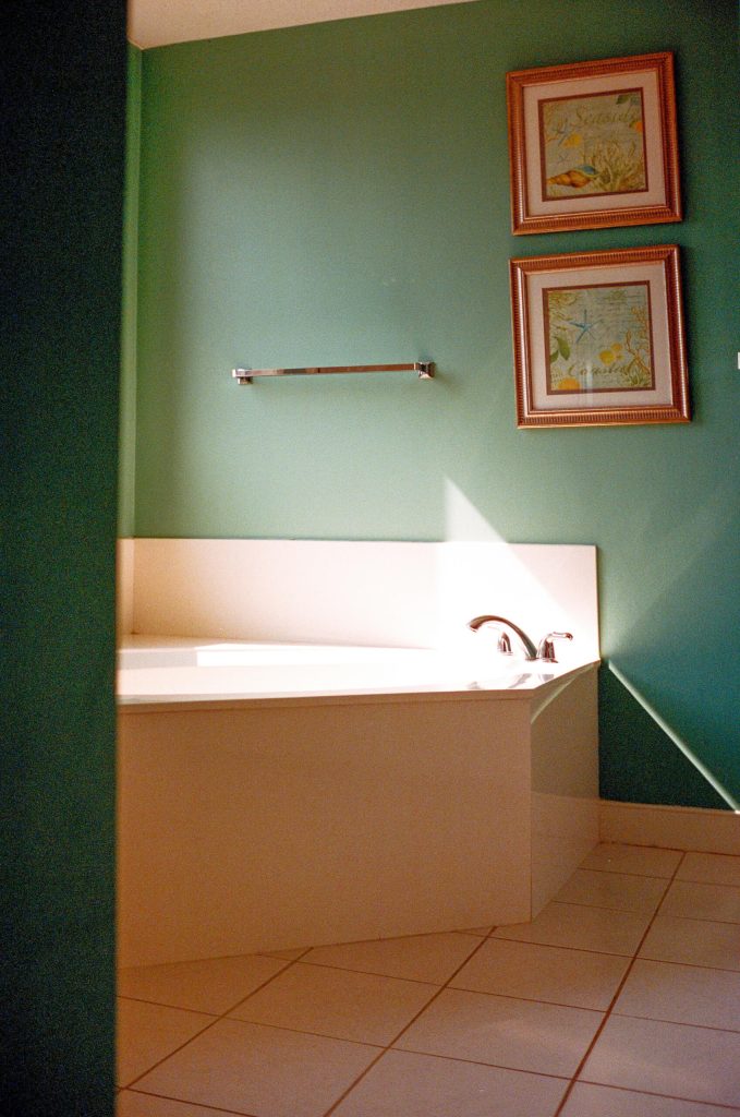 Bathroom featuring a green accent wall, bathtub, and horizontal grab bar for safety